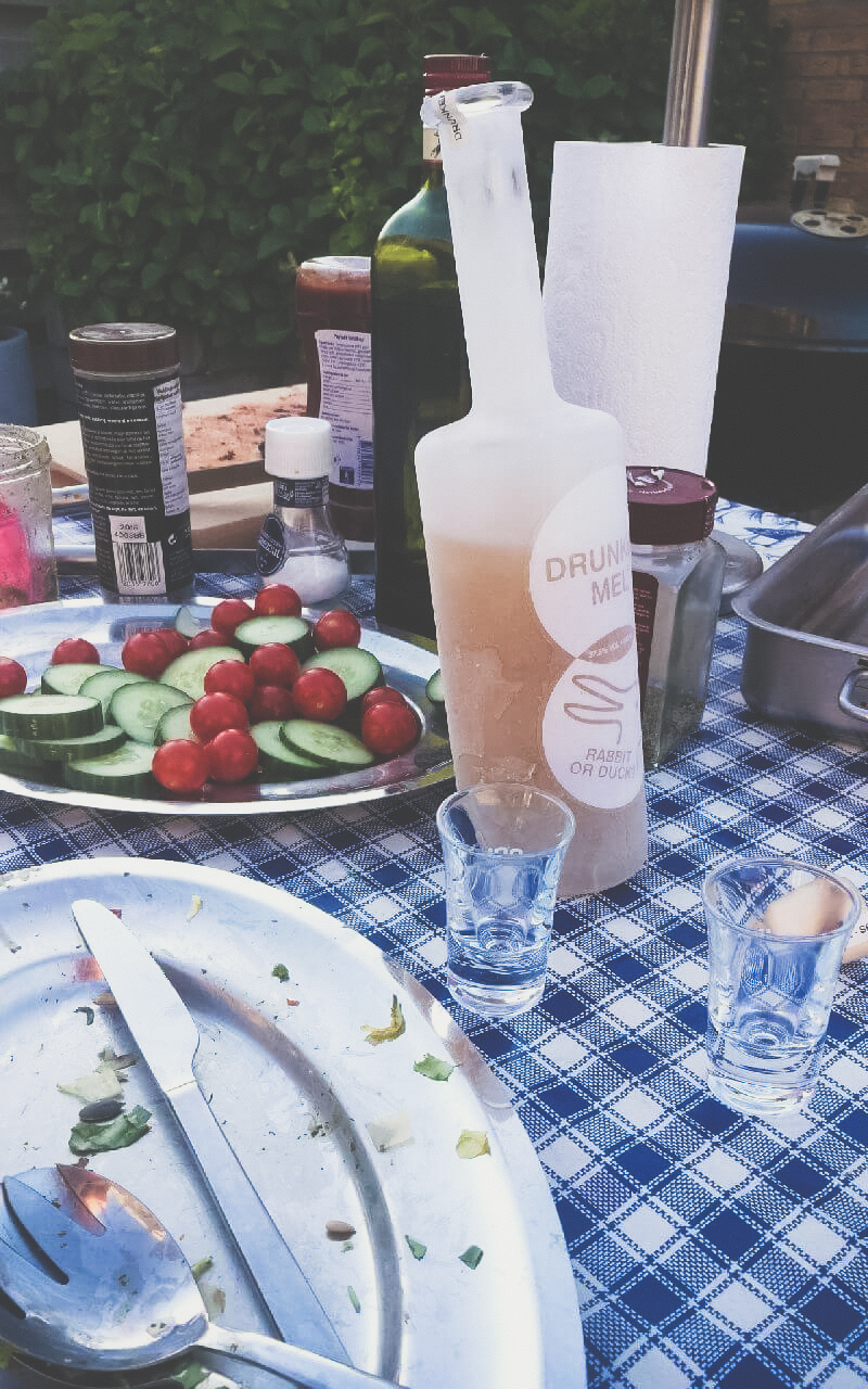 Bevroren fles op tafel met 2 glaasjes en komkommer en tomaat