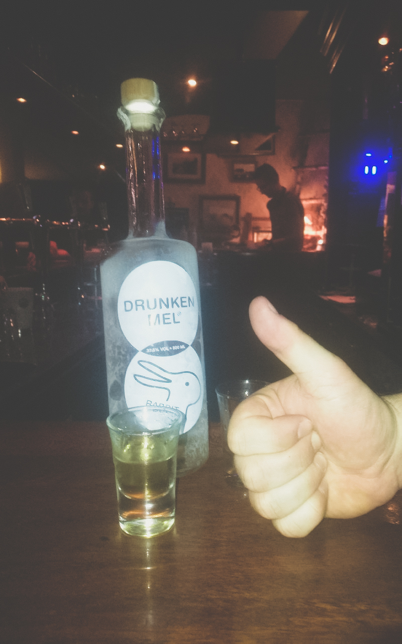 Duimomhoog met een fles drunken mel met een gevuld glaasje
