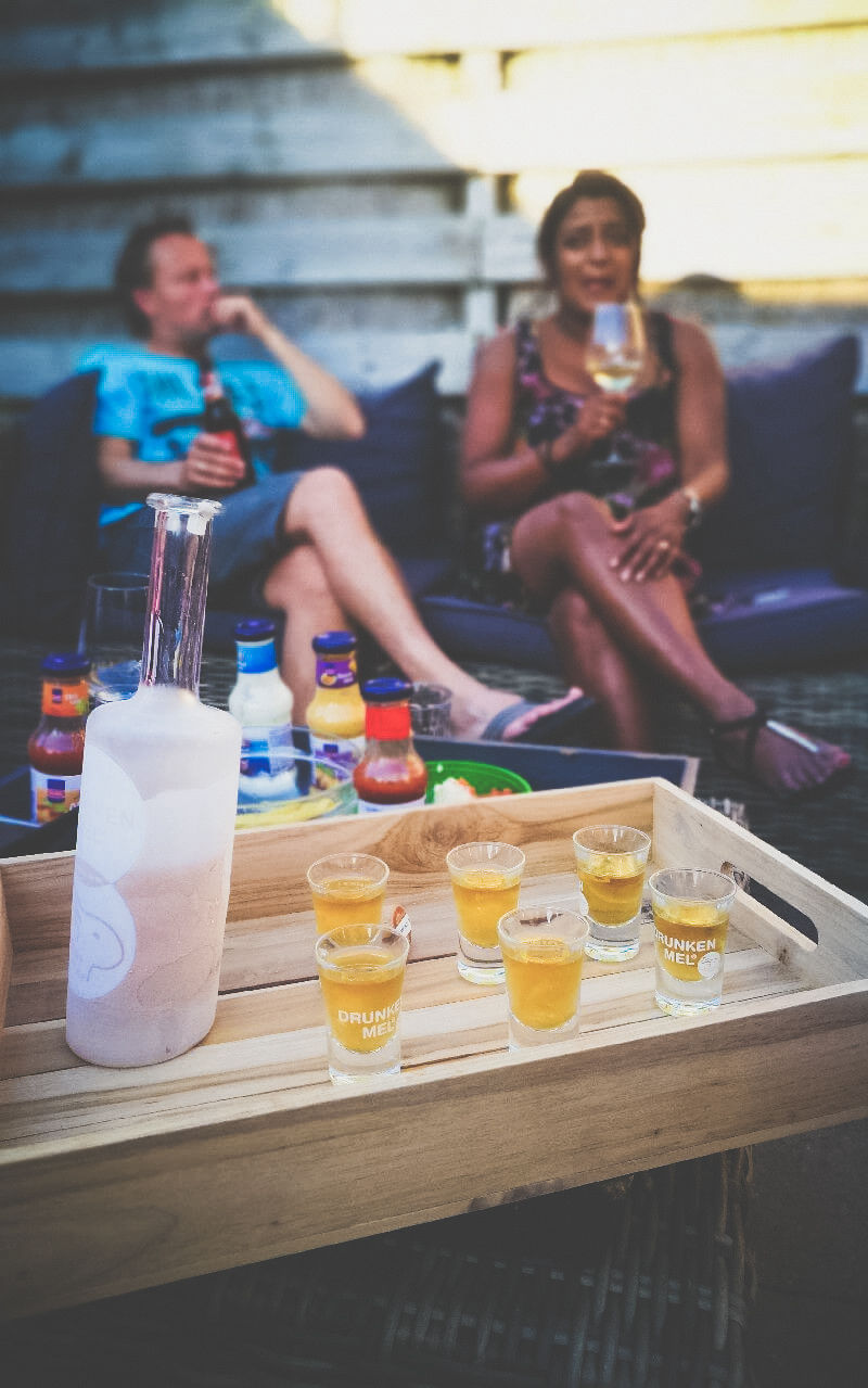 6 glaasjes karamel likeur op een houten dienblad met een bevroren fles in de tuin.