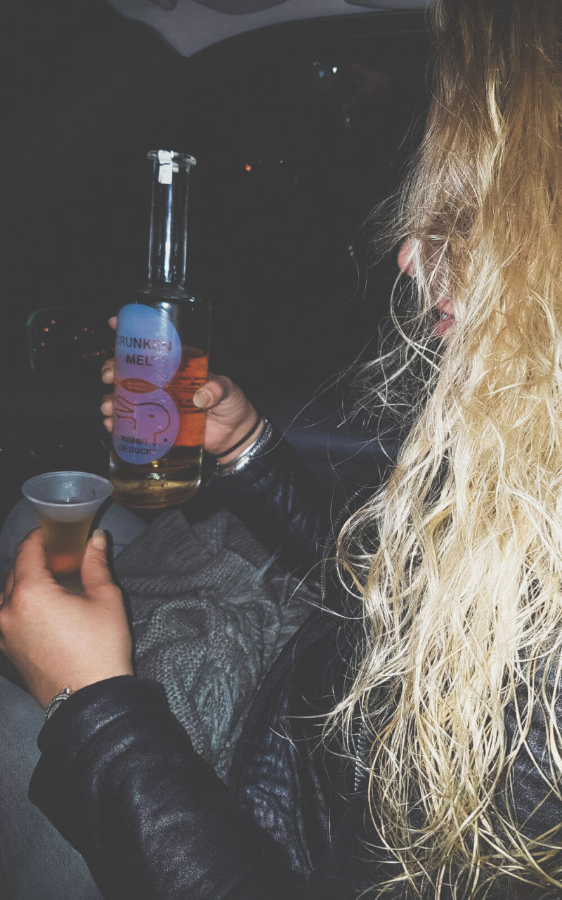 Blonde chick met een fles en glas Drunken mel in hara handen
