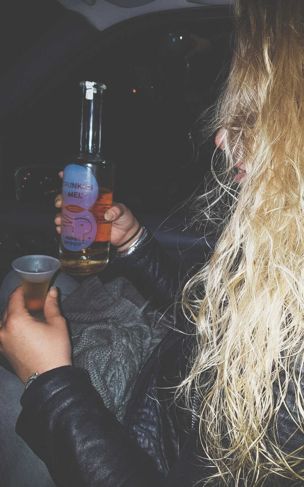 Blonde chick met een fles en glas Drunken mel in hara handen