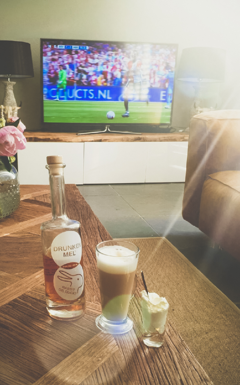koffie met slagroom en caramel likeur op tafel met voetbal op de achtergrond