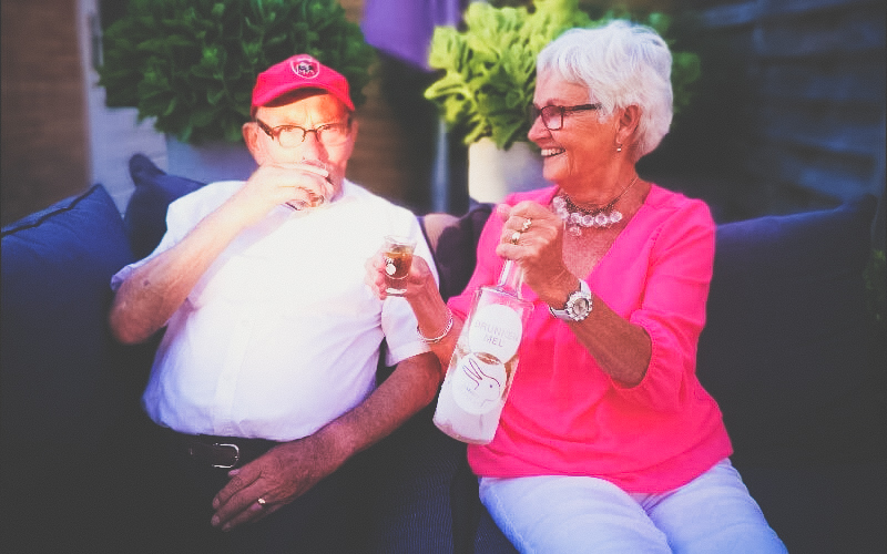 Opa en Oma proosten op het eleven met een glimlach samen en houden bevroren fles drunekn mel vast