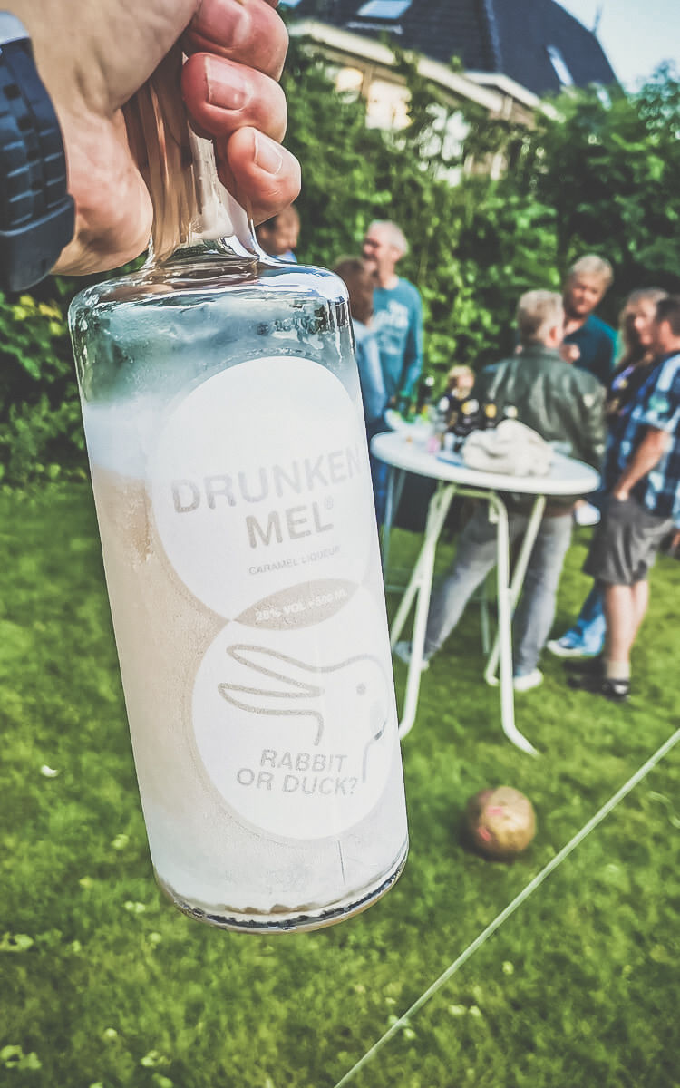 bevroren koude fles in de hand buiten in de tuin met mensen op de achtergrond