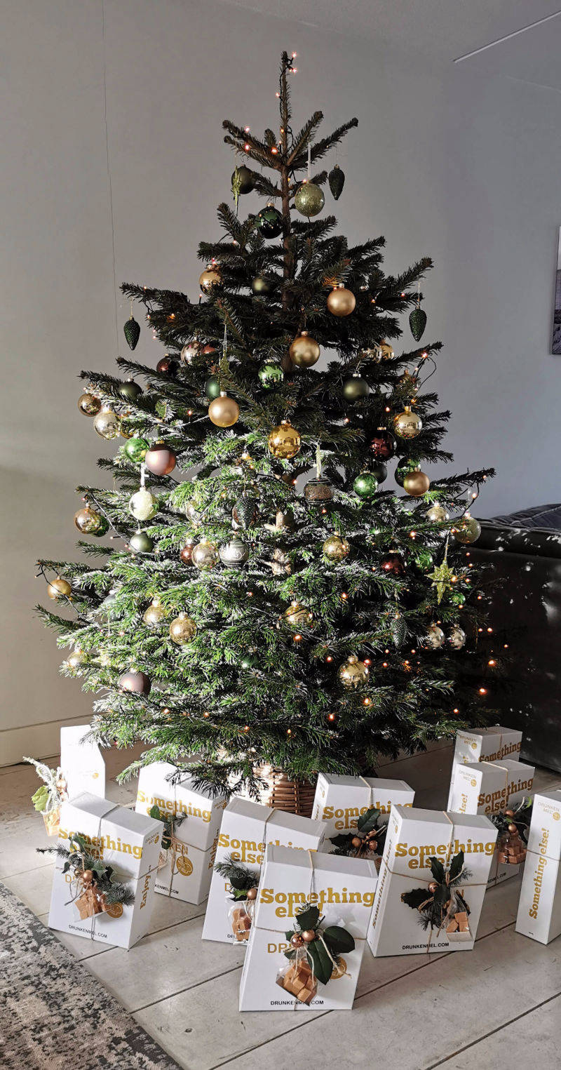 Kerstboom versierd met witte giftbxen van Drunken Mel eronder